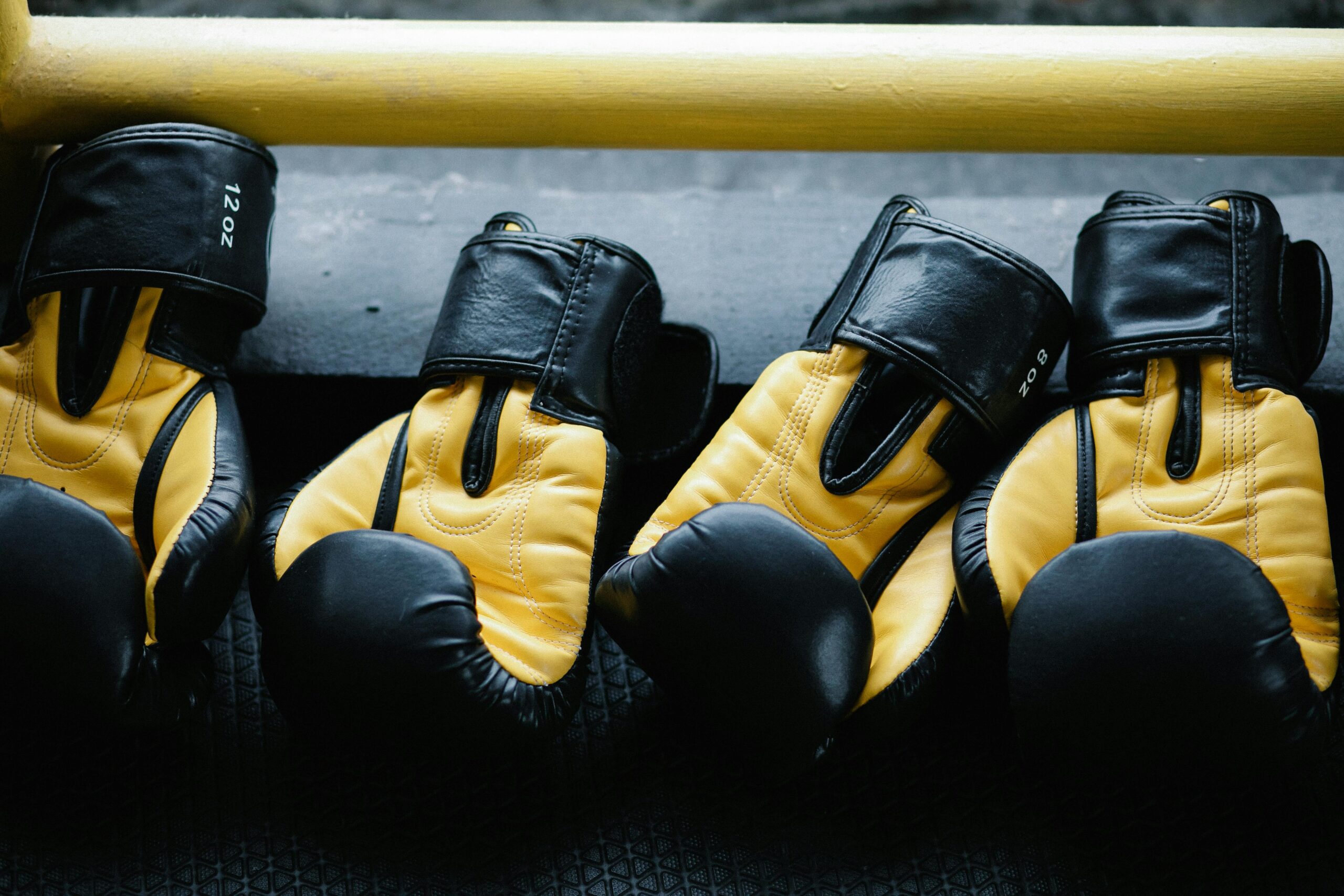 Pair of yellow and black boxing gloves resting on a gym floor.
